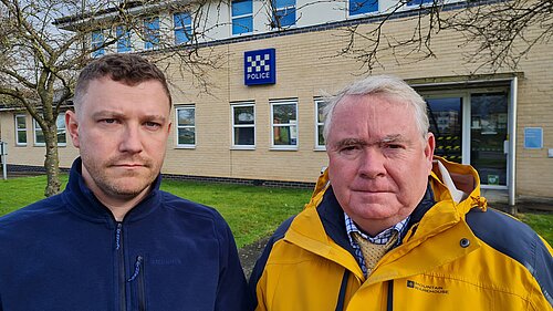 Henry Batchelor and Peter McDonald in front of a police station